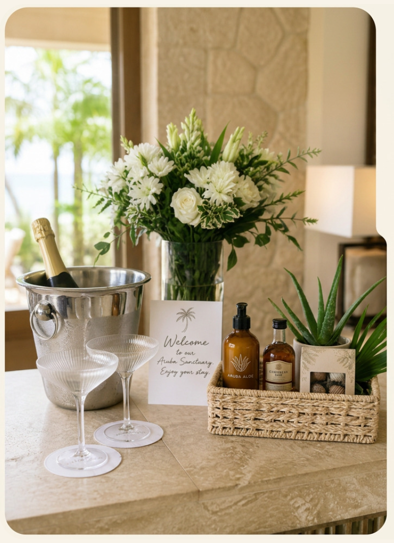 Champagne on ice, white florals, Aruba aloe amenities and local rum arranged on a stone counter with a palm-motif welcome card
