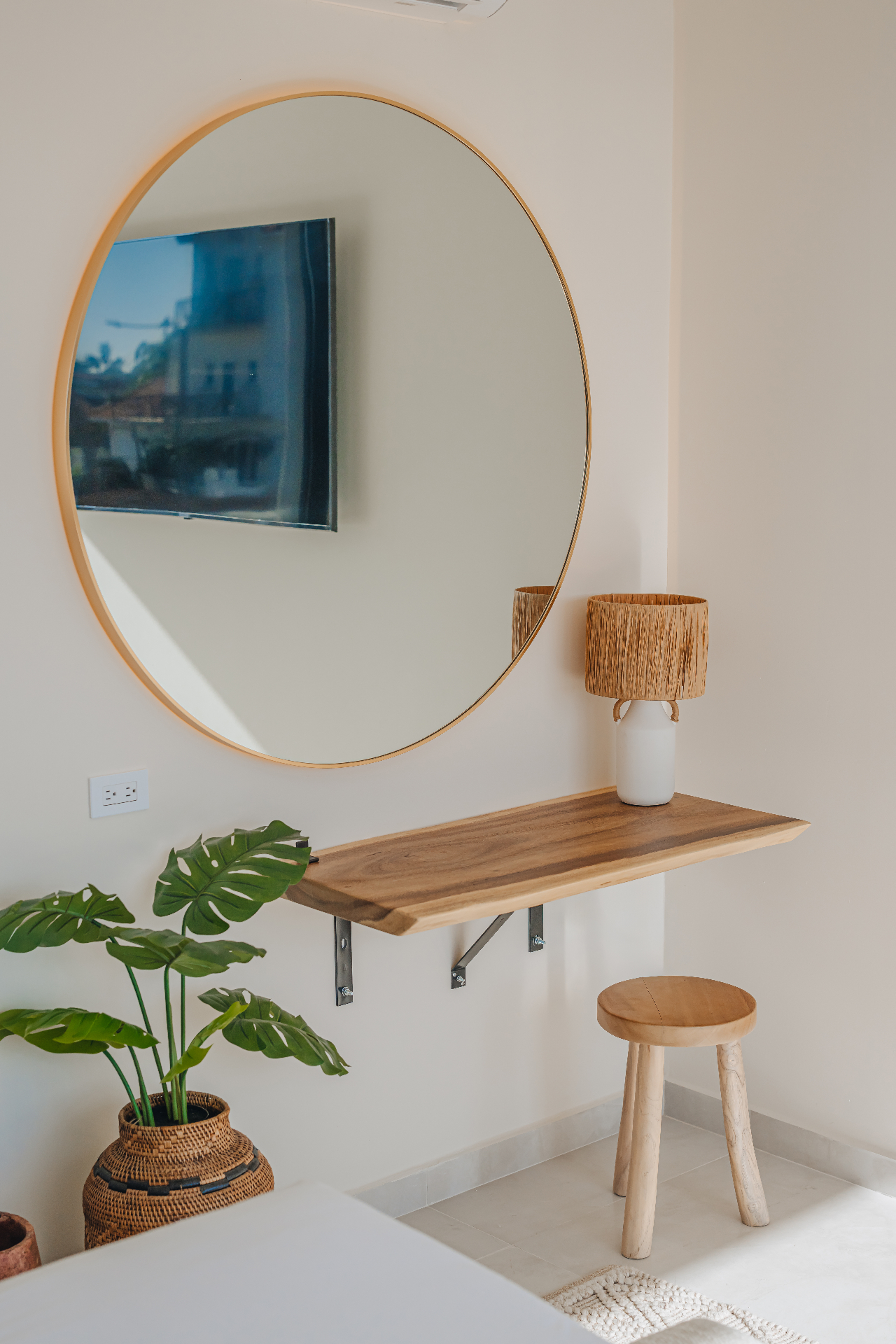 Round brass mirror above a live-edge wood shelf