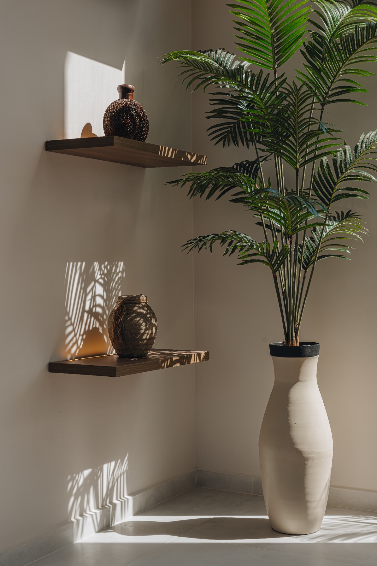 Sunlit corner with ceramic vessels and a palm casting soft shadows