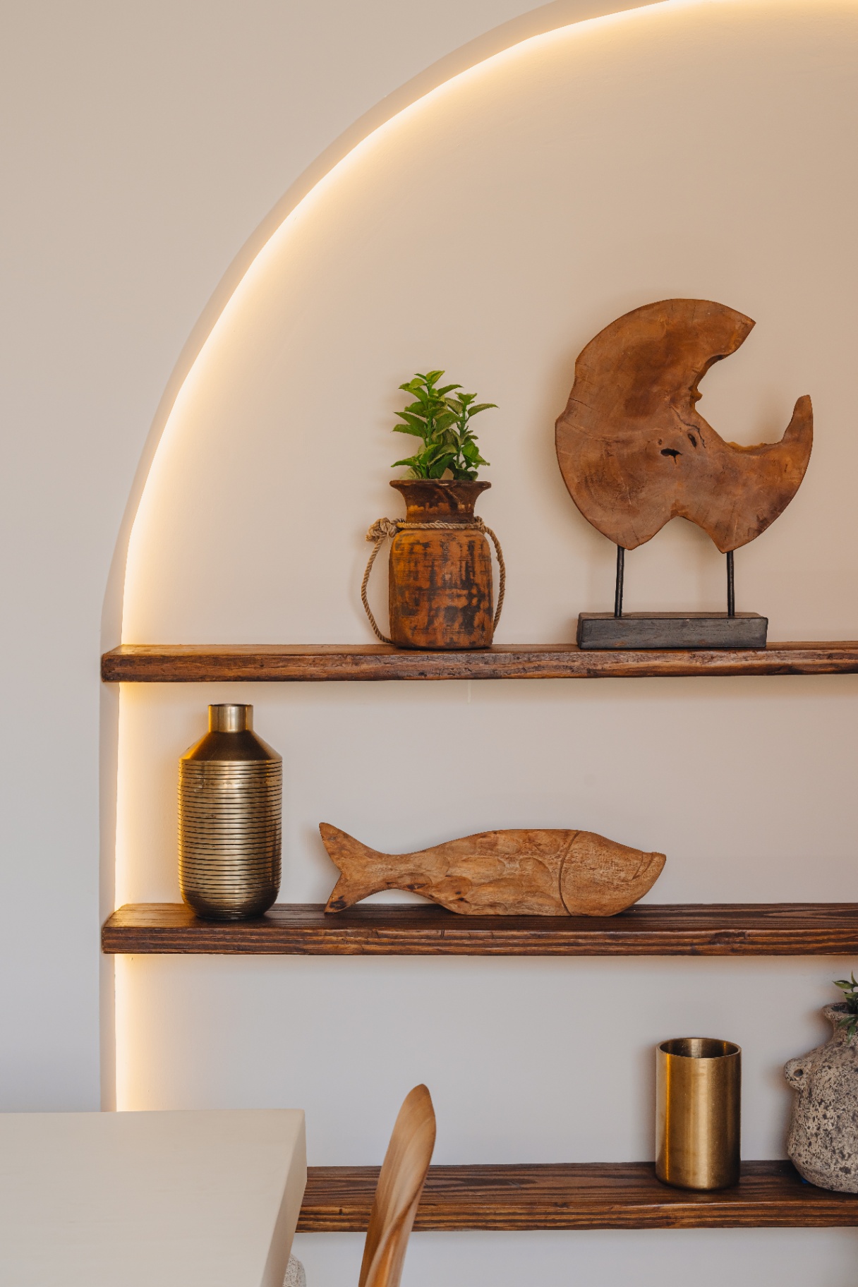 Arched niche with warm cove lighting and hand-carved wooden objects